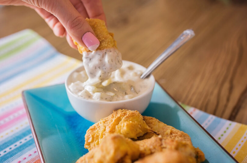 photo showing dipping homemade fish sticks into tarter sauce