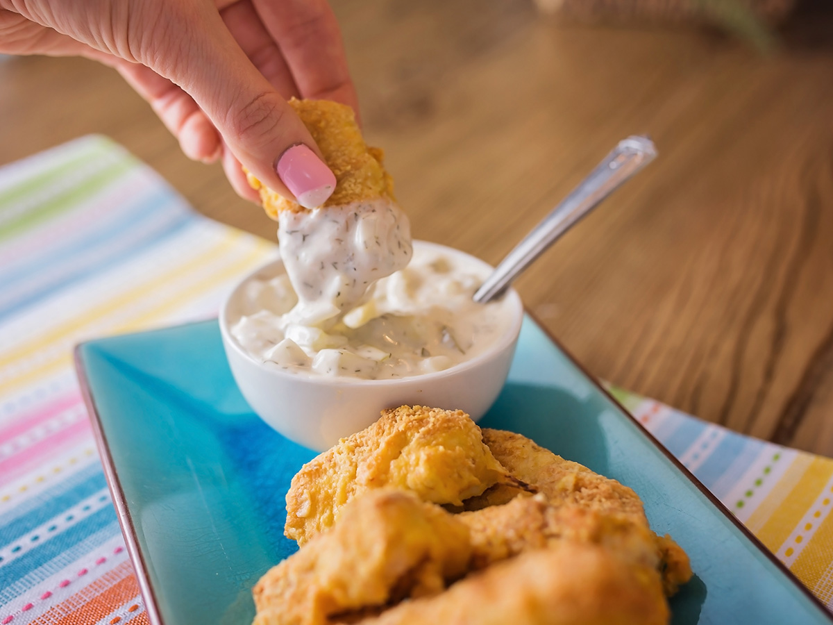 photo showing dipping homemade fish sticks into tarter sauce