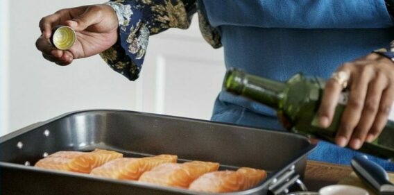 Cooking tips show how seafood is simple. Here a woman seasons salmon to bake in the oven